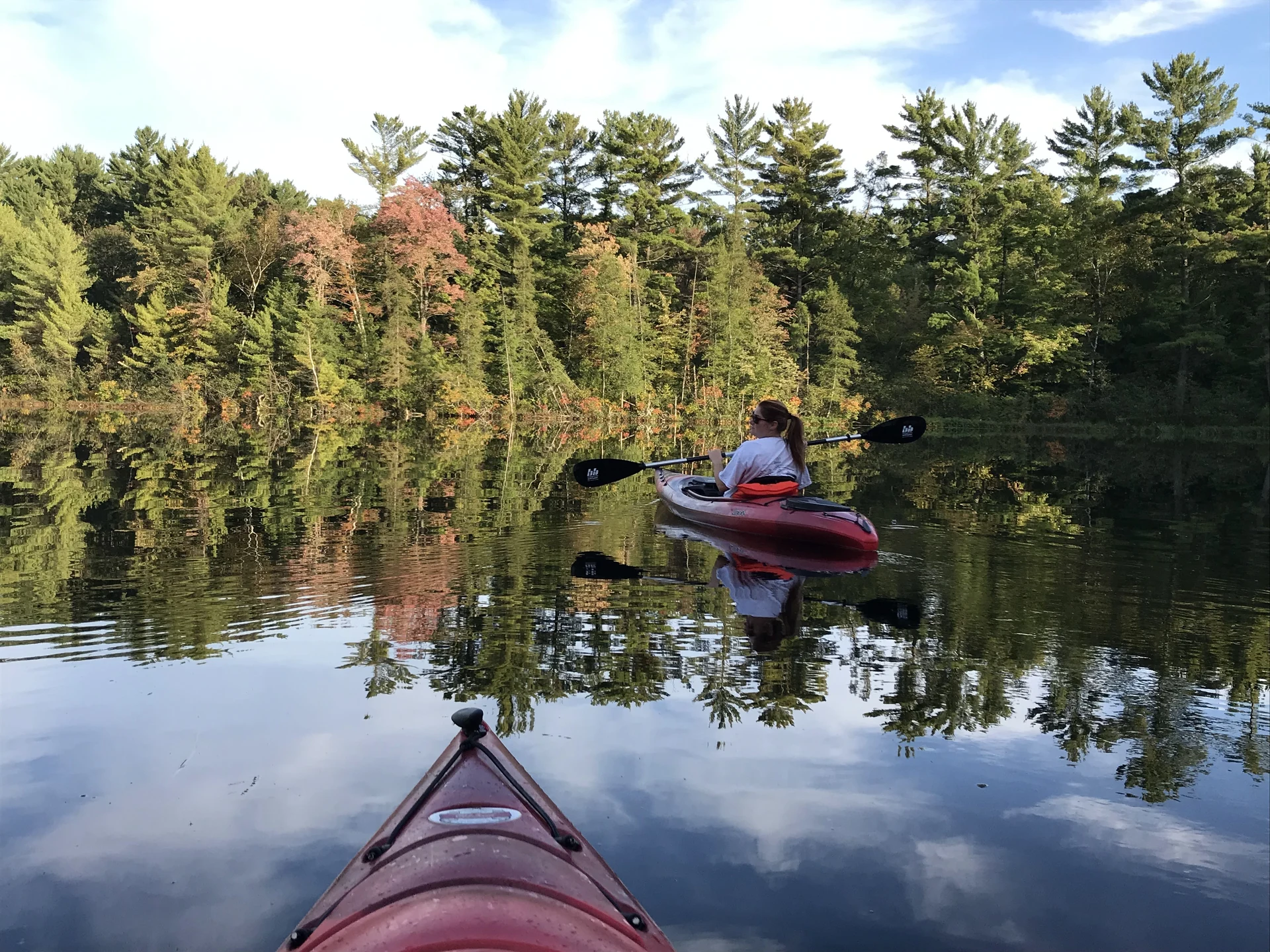 Kayaking on calm water with reflections of autumn trees