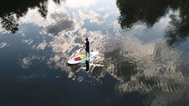 Paddleboard on reflective water, from Adventure Outfitters’ photo collection